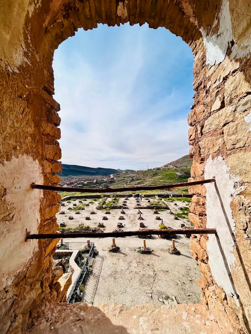 View through an arched opening over the ruins of Beni Hammad