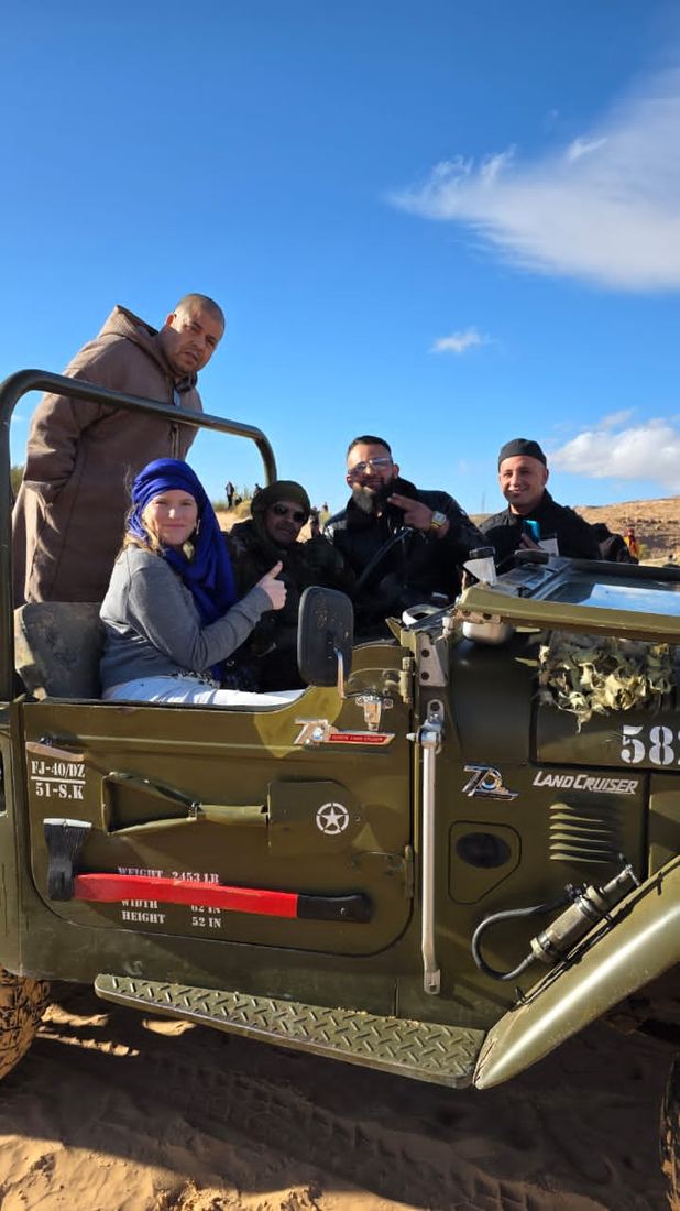 Travellers and their driver in an open-topped 4×4 under a clear desert sky