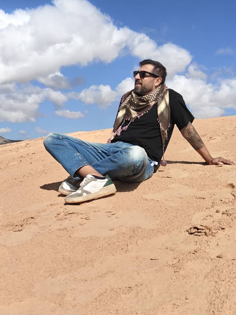 A traveller leaning back on a sand dune in the sun