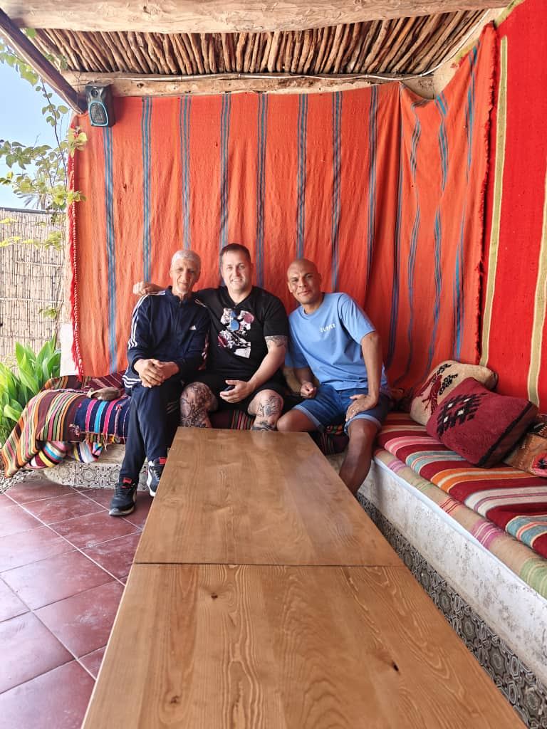 Three travellers on a striped banquette under a red canopy