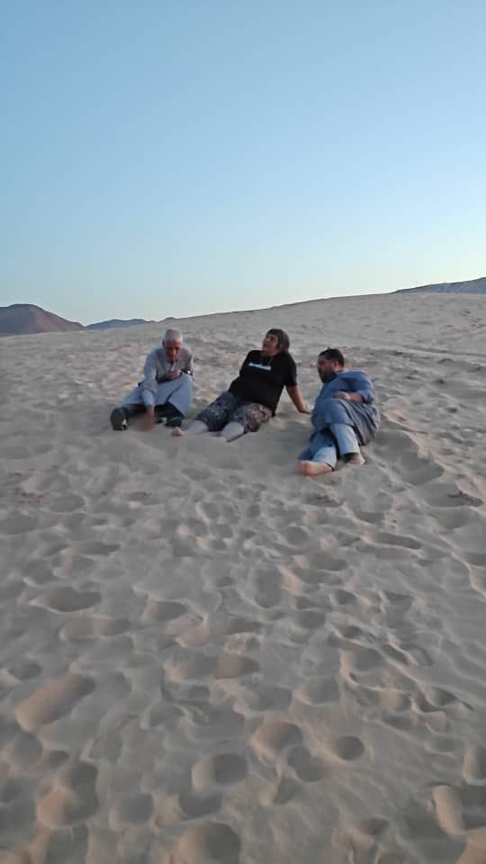 Three people sitting on a sand dune in the evening light