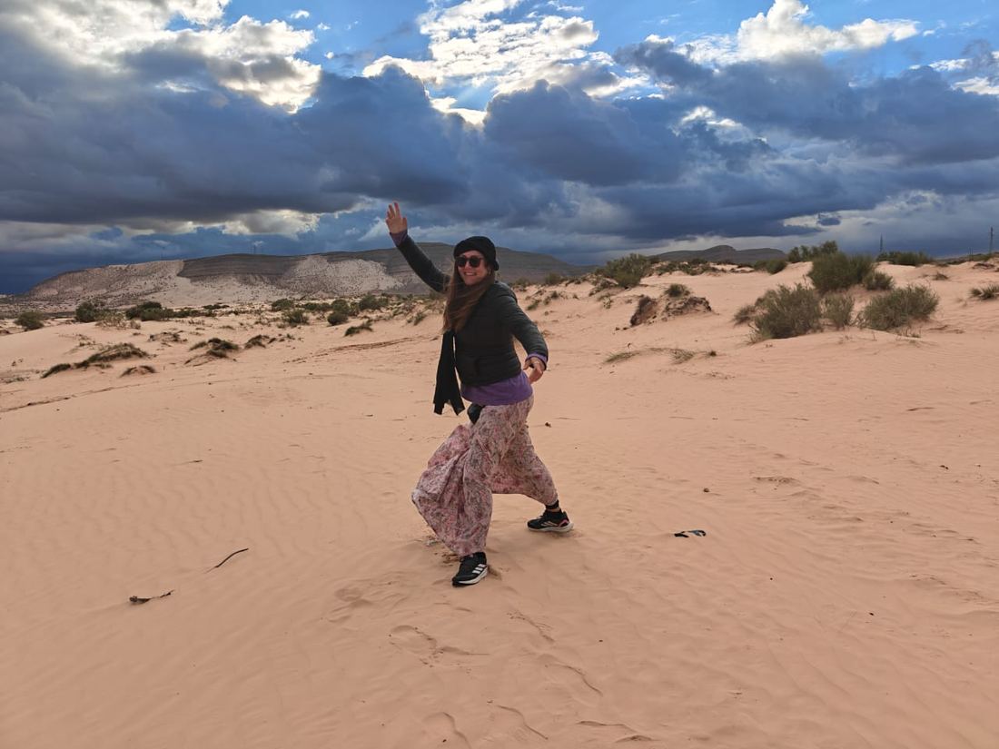 A traveller dancing on the dunes under a sky of heavy clouds