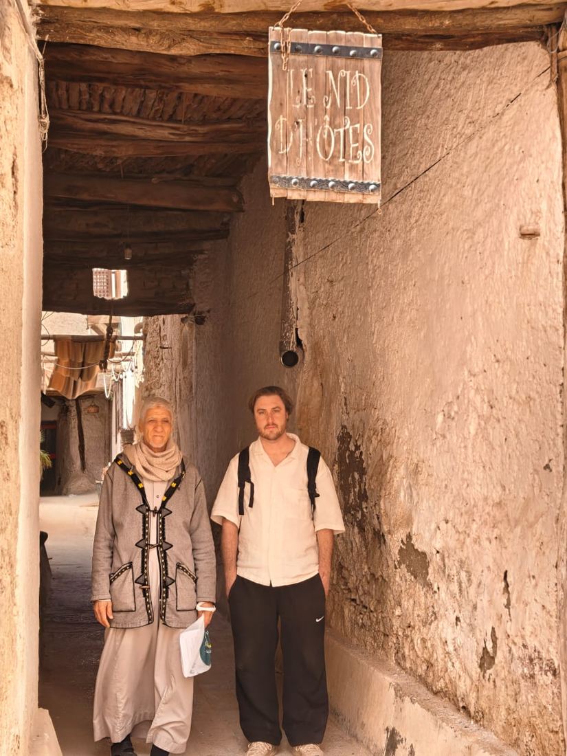 A traveller and a local guide in a narrow covered lane between earthen walls