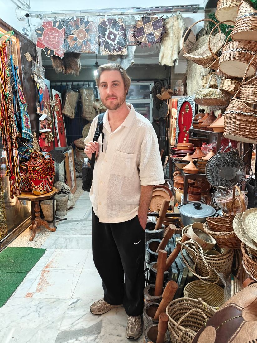 A traveller in a narrow shop hung with baskets, pottery and rugs