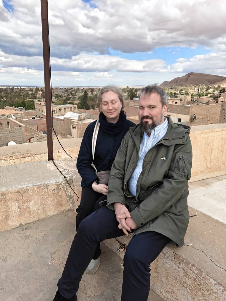 A couple sitting on a rooftop above a flat-roofed desert town