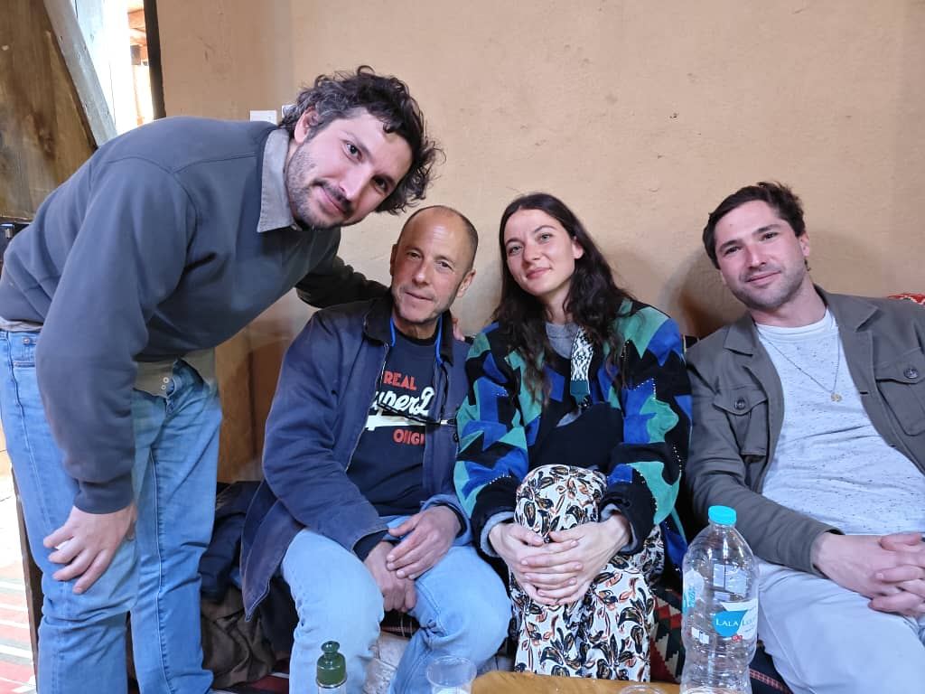Four travellers squeezed together on a banquette, smiling for the camera