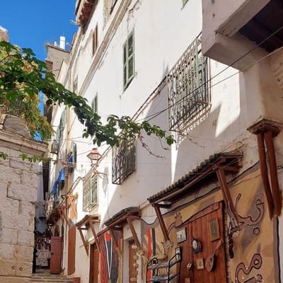 A stepped cobbled lane in the Casbah of Algiers, brass and copperware laid out at a doorway