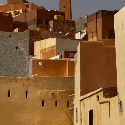 Ochre and whitewashed rooftops of a M'Zab town stacked up towards its plain pyramid minaret
