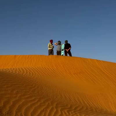 Three travellers on the crest of a golden dune
