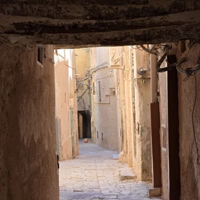 A flagstoned lane running under the covered passages of a M'Zab ksar towards the light