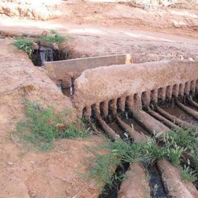 A stone foggara divider sharing out water between the garden channels of an oasis near Timimoun