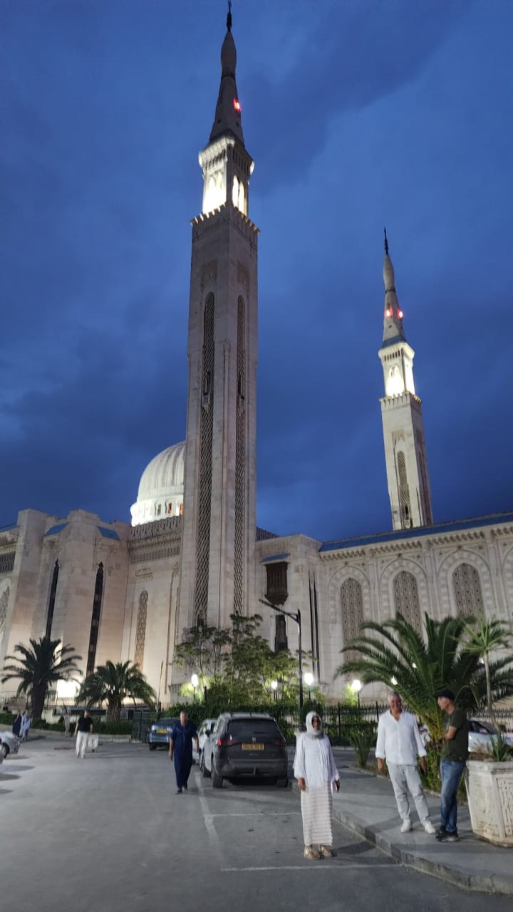 The twin minarets and dome of the Emir Abdelkader Mosque in Constantine, floodlit at dusk