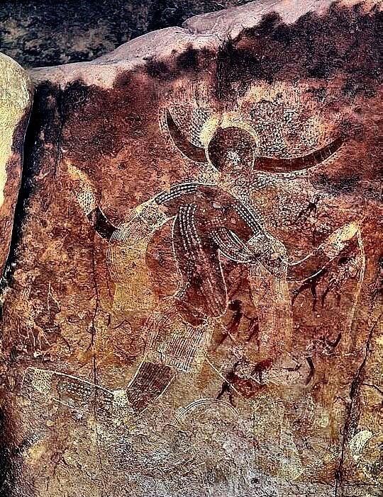 A prehistoric painting of a horned figure in dotted patterns in the Tassili n'Ajjer