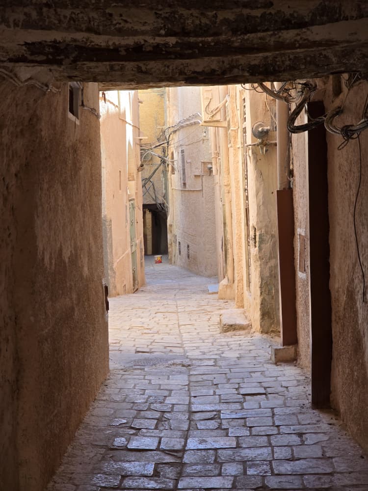 A flagstoned lane running under the covered passages of a M'Zab ksar towards the light