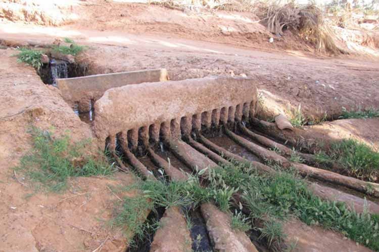 A stone foggara divider sharing out water between the garden channels of an oasis near Timimoun