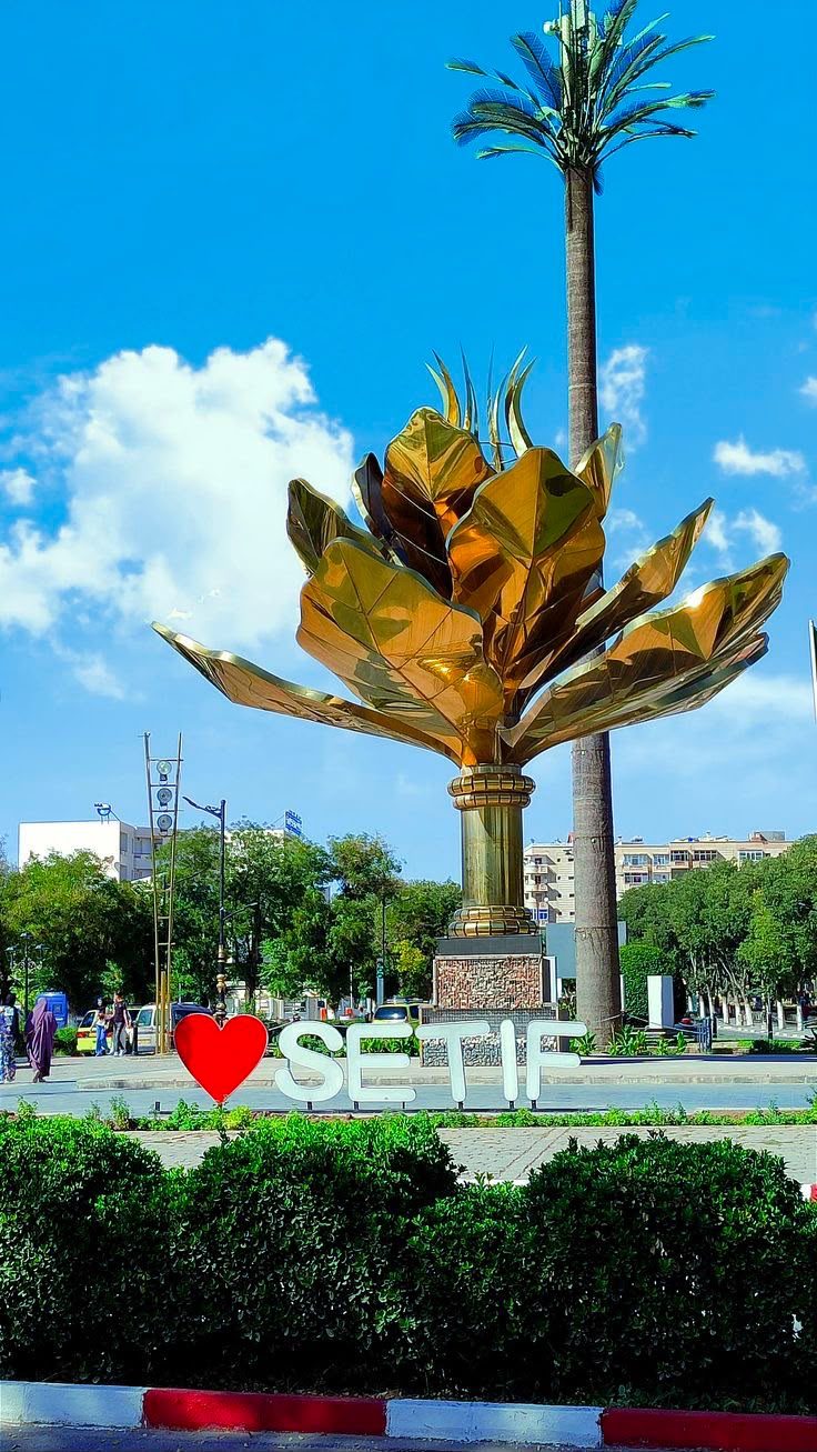 Golden flower sculpture and the Sétif city sign in a park
